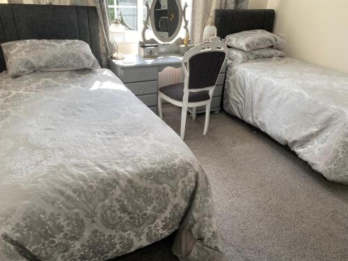 贝辛斯托克Tower Hill House Basingstoke的一间卧室配有两张床、一张桌子和一把椅子