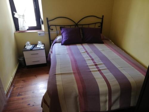 卡韦松·德·拉·萨尔Pensión Rosa的一间卧室配有带条纹棉被的床和窗户