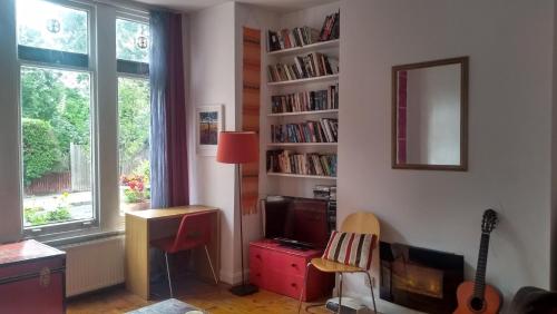伦敦Homey, warm & welcoming room.的客厅配有电视和带书籍的书架