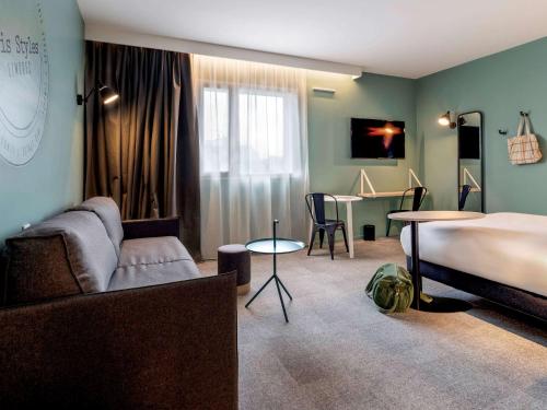 里摩日ibis Styles Limoges Centre的一间卧室配有一张床、一张沙发和一张桌子