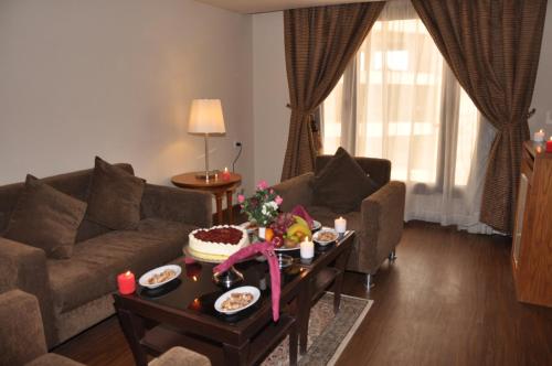 利雅德Reef Al Malaz International Hotel by Al Azmy的客厅配有沙发和餐桌,餐桌上摆放着食物