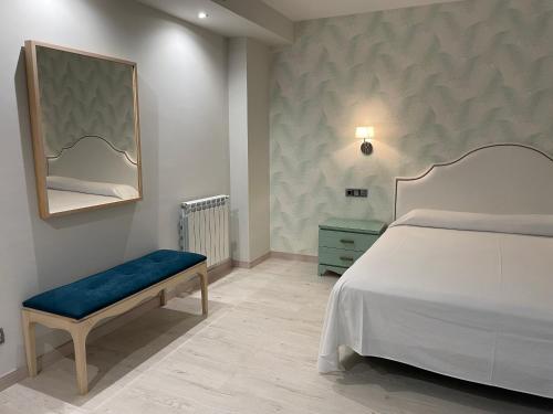 艾因萨比利牛斯艾茵莎酒店的一间卧室配有一张床、一张长凳和镜子