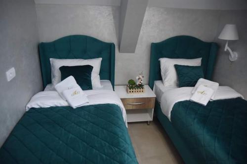兹拉蒂博尔Apartman Aura Hills Zlatibor的配有绿色软垫床的客房内的两张床