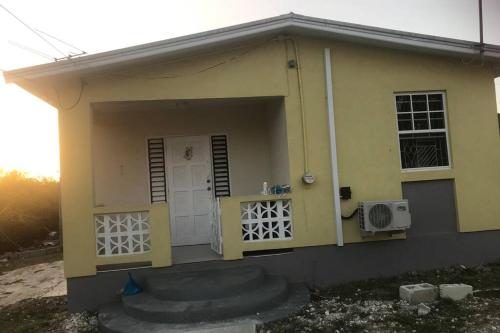 基督教堂市Sasha’s Holiday Home Oistins Barbados的一个小黄色房子,设有门窗
