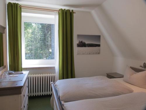 克林根塔尔慕勒申菲尔恩酒店的一间卧室设有床铺和一个带绿色窗帘的窗户。