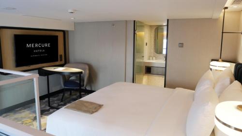 泗水Mercure Surabaya Manyar的酒店客房设有白色的床和电视。