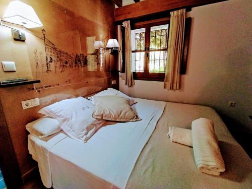 格拉纳达Apartamentos Alhambra的一间卧室配有带白色床单和枕头的床。