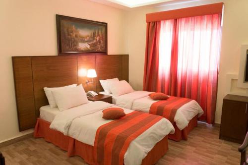 瓦迪穆萨hidab petra的酒店客房,配有两张带红色窗帘的床