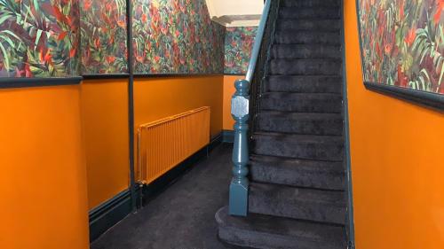 布莱克浦Tropics Beach Hotel的橙色走廊设有楼梯,墙上挂有绘画作品
