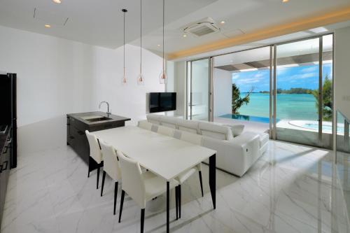 恩纳Villa VALIOSA ON THE BEACH的厨房以及带白色桌椅的用餐室。