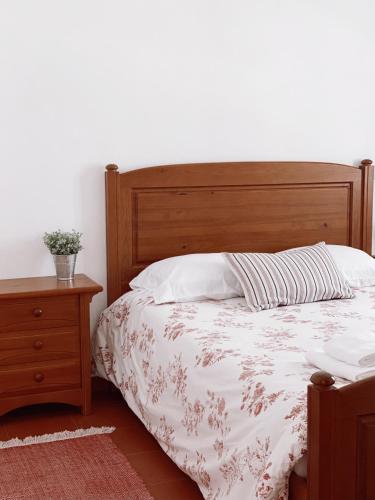 圣佩罗德姆Casa dos Pinheiros的一间卧室配有一张带木制床头板和一张桌子的床。