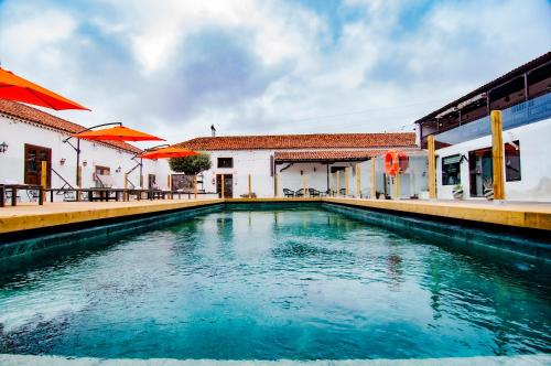 洛斯雷亚莱霍斯Hotel Rural Jardines de Milano的一座带橙色遮阳伞的建筑前的游泳池