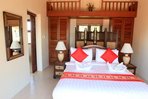 高兰Baan KanTiang See Villas - SHA Extra Plus的一间卧室配有一张带红色枕头的大床