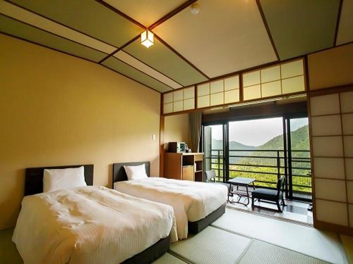 箱根Hakone Kowakien Mikawaya Ryokan的酒店客房设有两张床和一个阳台。