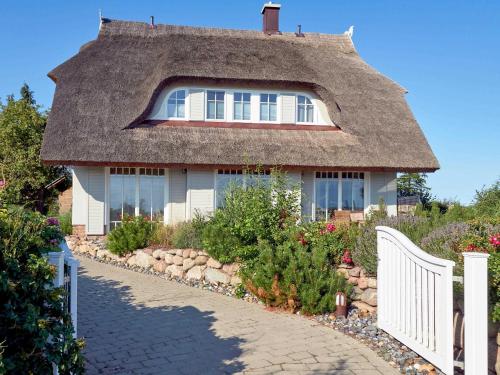奥特里德维茨Reethus Reddevitz F 402 mit Kamin, Sauna, Terrasse, Boddenblick的茅草屋顶和白色围栏的房子