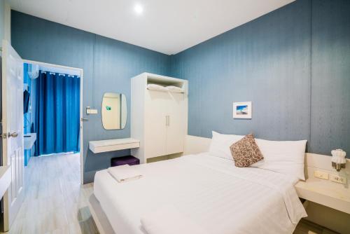 素叻Paragon Hometel的卧室配有白色的床和蓝色的墙壁
