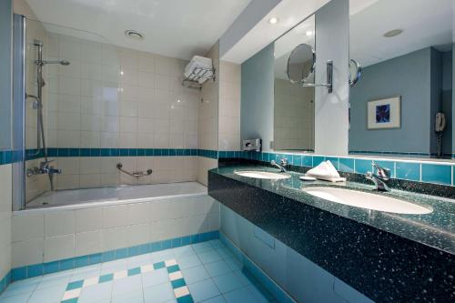 安卡拉安卡拉丽笙布鲁酒店的浴室设有2个水槽、浴缸和镜子