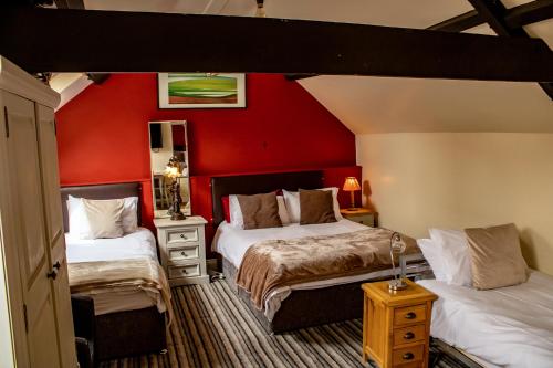 查尔德The Dolphin Hotel的一间卧室设有两张床和红色的墙壁