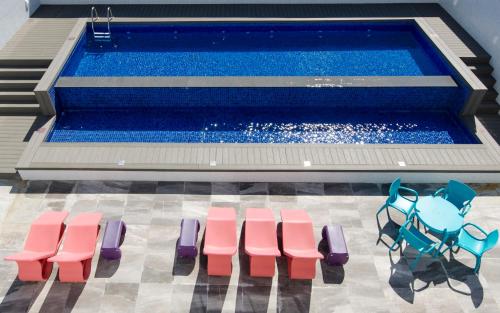 巴拉奈里奥-坎布里乌Ibis Styles Balneário Camboriú - 1 Quadra do Mar的游泳池旁的游泳池配有粉色和蓝色椅子