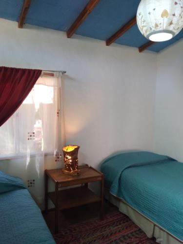HorconCabaña Canto del Viento, 4 personas的一间卧室配有两张床和一张带台灯的桌子