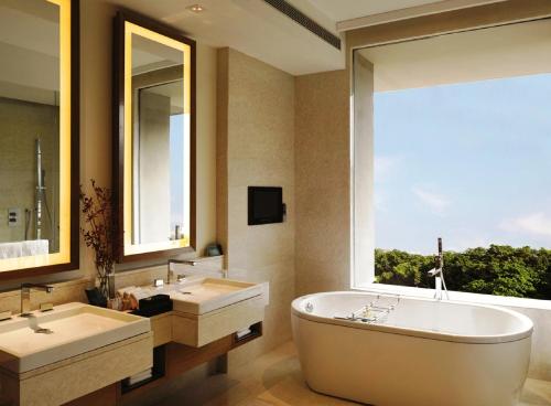 古尔冈古尔冈奥博罗伊酒店的一间带两个盥洗盆、浴缸和窗户的浴室