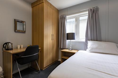KirmingtonNightel Hotel的配有一张床、一张书桌和一扇窗户的酒店客房