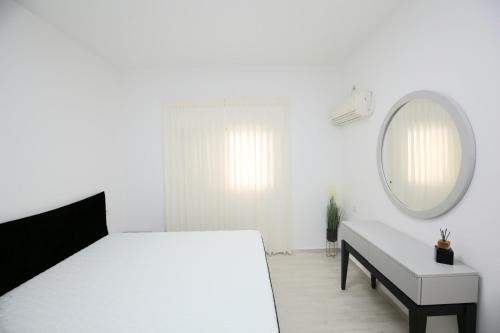 内坦亚City center luxury apartment in Netanya的白色卧室配有床和镜子