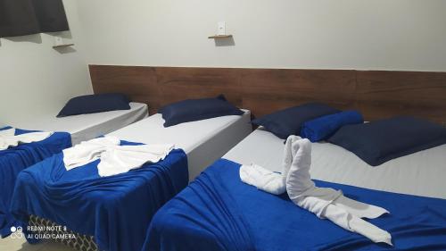 阿帕雷西达Pousada Quarto com frigobar,ar e garagem gratuita的配有蓝色床单和蓝色枕头的三张床