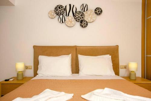 基萨莫斯Mare Monte Luxury Apartment的一张带两个白色枕头的床和墙上的时钟