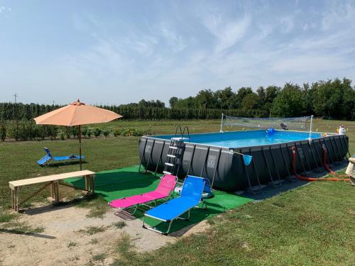 费拉拉Borgo Tarapino的一个带椅子和桌子的游泳池以及一把遮阳伞