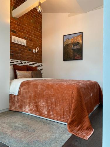 考纳斯Jolie Apartments的一间卧室设有一张带砖墙的大床