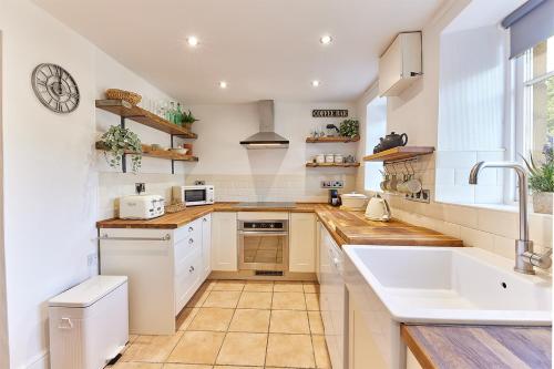 OvinghamHost & Stay - Waterleap Cottage的厨房配有白色橱柜和水槽