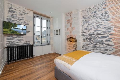 昂热Hyper Centre 16 rue Valdemaine的一间卧室设有砖墙、一张床和一台电视。