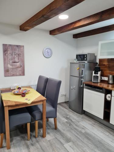 卡佩尔-格拉芬豪森Haus Schneider的厨房配有木桌、椅子和冰箱。