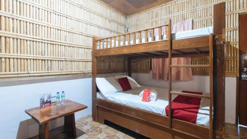 ZambalesRedDoorz Hostel @Megans Paradisio Beach Resort的一间卧室设有两张双层床和一张桌子