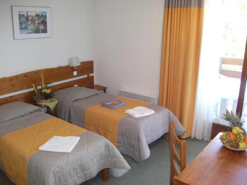 普雷芒翁VVF Jura Les Rousses的酒店客房设有两张床和一张桌子。