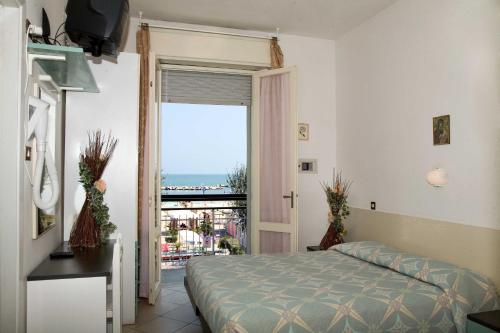 里米尼天堂酒店的一间卧室配有一张床,享有海景