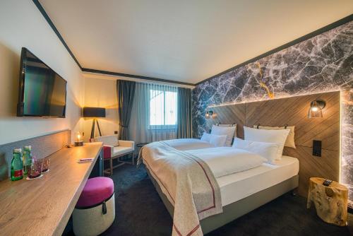 萨尔茨堡FourSide Hotel Salzburg的酒店客房设有一张大床和一张书桌。