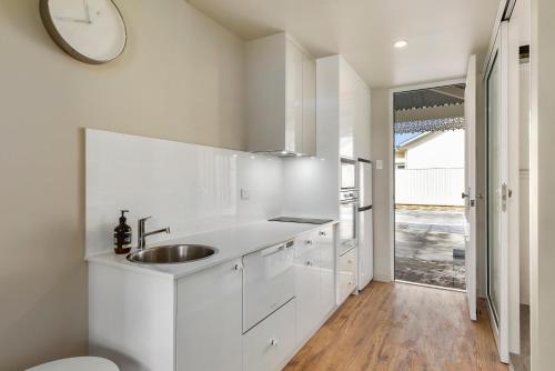 纳拉库特Aloha Central Luxury Accommodation的白色的厨房,配有水槽和墙上的时钟