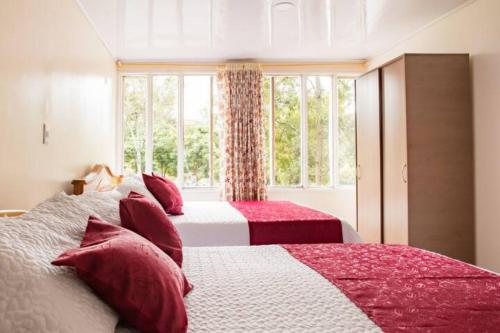 波哥大Touristic House的一间卧室配有两张红色和白色床单