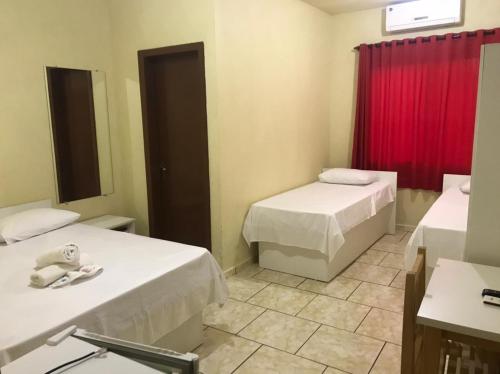 Nova Santa MedianeiraHotel Dom Alcides的一间设有两张床和红色窗帘的房间