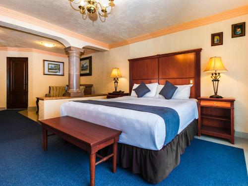 托卢卡Quinta del Rey Hotel的酒店客房设有一张大床和一张桌子。