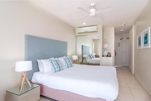 凯恩斯湖滨大道201号酒店的卧室配有白色的床和吊扇