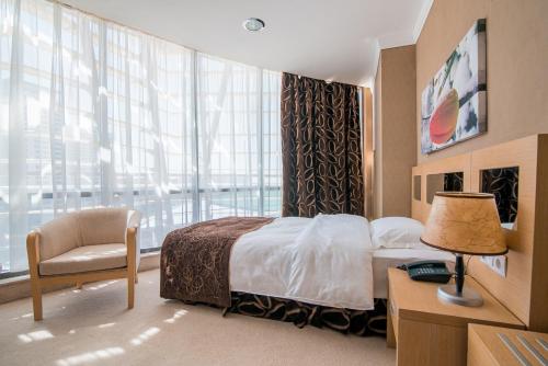 阿斯塔纳Alau Hotel的卧室配有床、椅子和窗户。