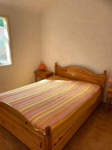 卢米奥Location 5 personnes Sant Ambroggio Cocody village的一间卧室配有木床和2个床头柜