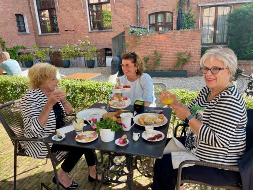 米德尔堡罗斯福精品酒店的三个女人坐在餐桌上吃着食物