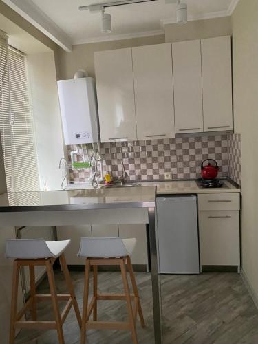 博尔若米nikani1的厨房配有白色橱柜和2张凳子