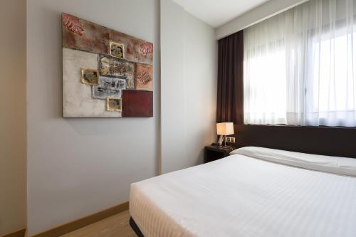 伊鲁尔特孙普拉萨奥拉酒店的卧室配有一张床,墙上挂有绘画作品