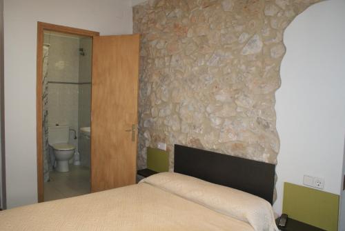 莱斯卡拉Pensió i Apartament Torrent的一间卧室设有一张床和石墙