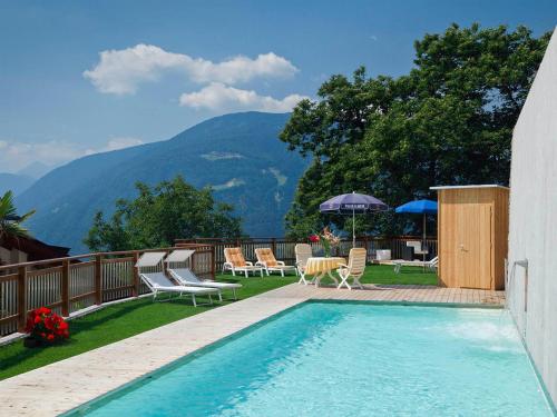 蒂鲁罗Residence Innerfarmerhof的一个带椅子的游泳池以及一座带山脉的露台